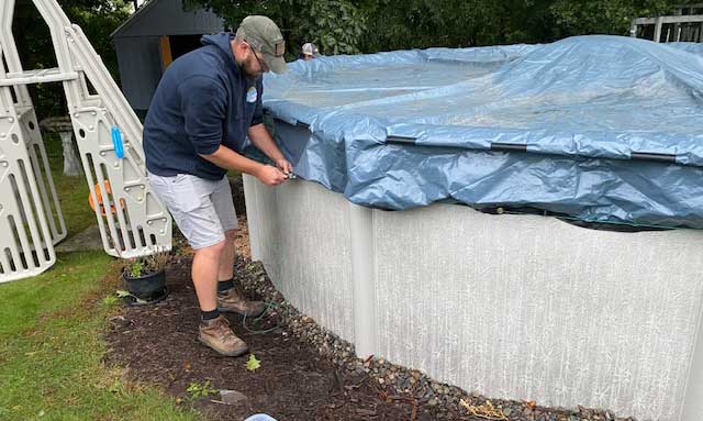 man installing a winter cover on their pool