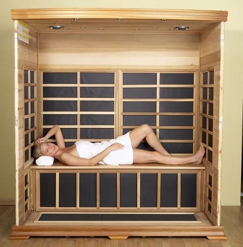 woman is relaxing in a wooden sauna with black panels